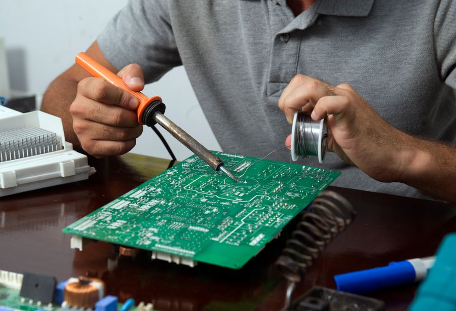 Engineer repairing a circuit board with a soldering iron