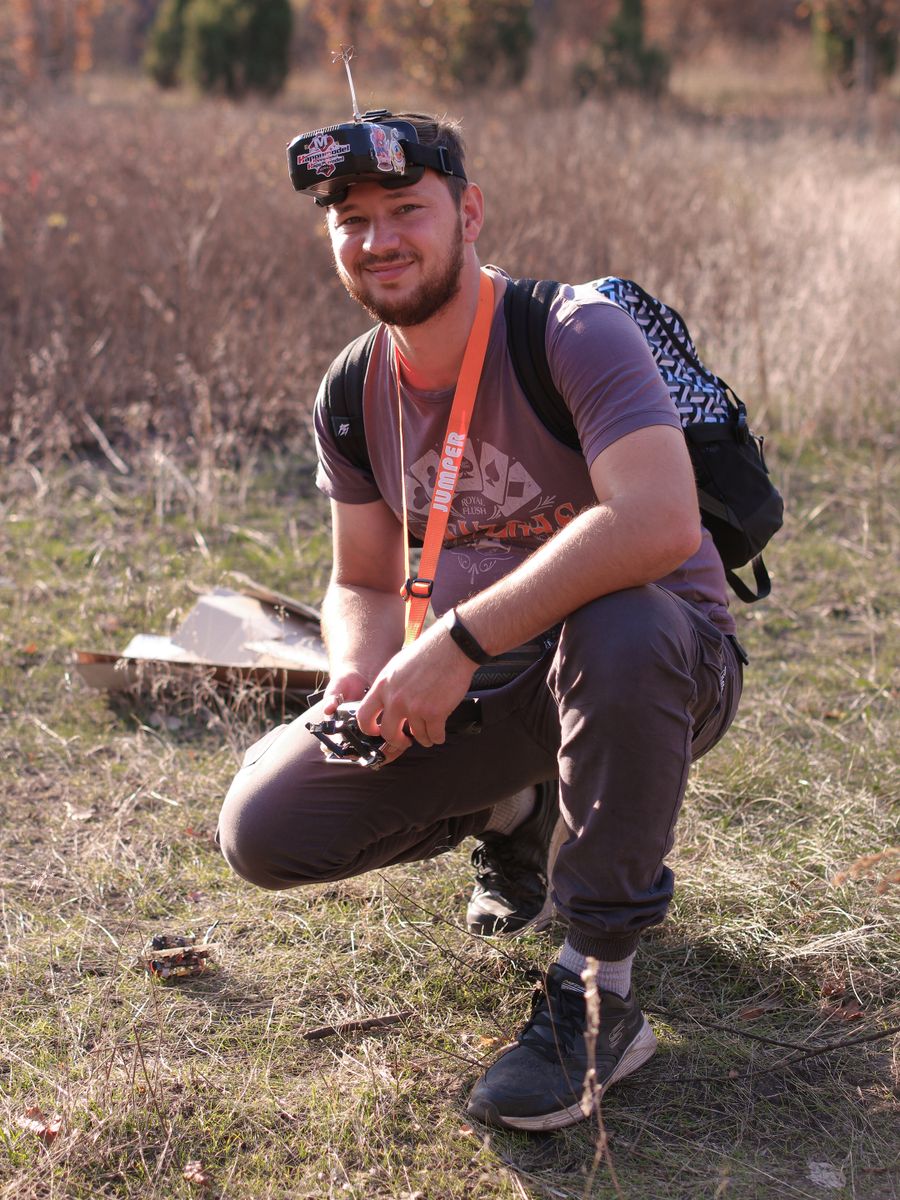 FPV pilot wearing video goggles beside a racing quadcopter